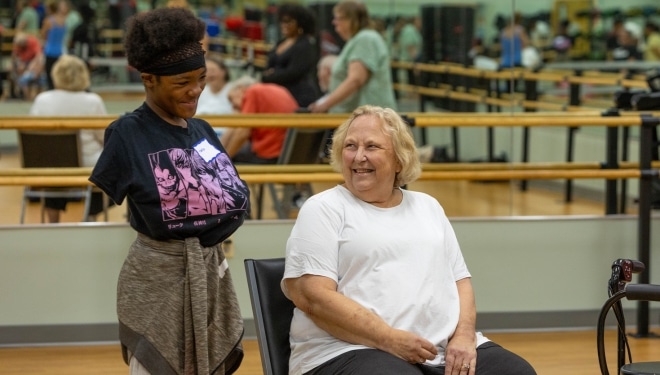 a woman sitting in a chair with a woman in the background