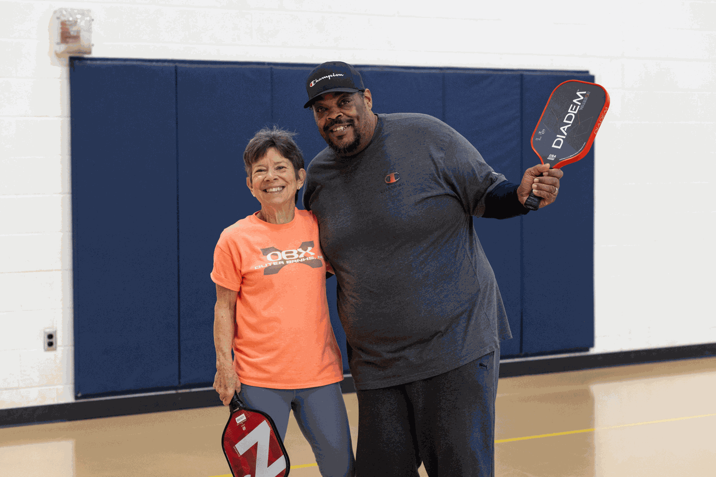 a man and woman holding paddles in a gym
