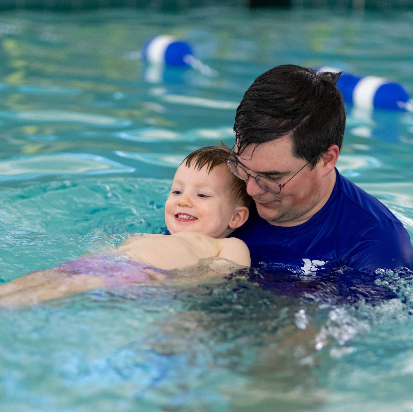 a man holding a baby in a pool