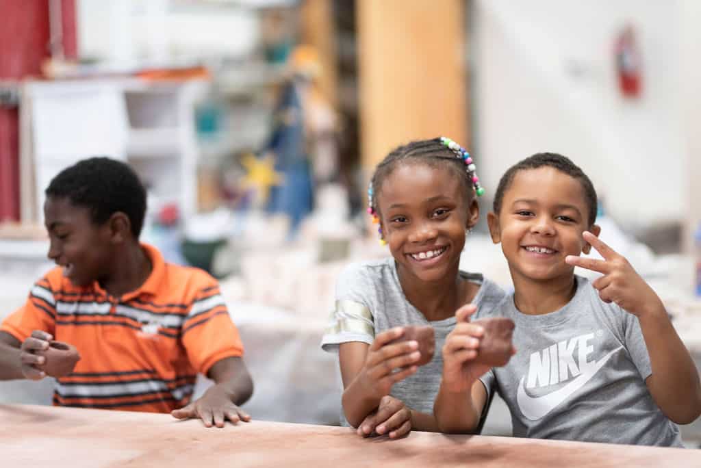 a group of kids smiling and holding clay