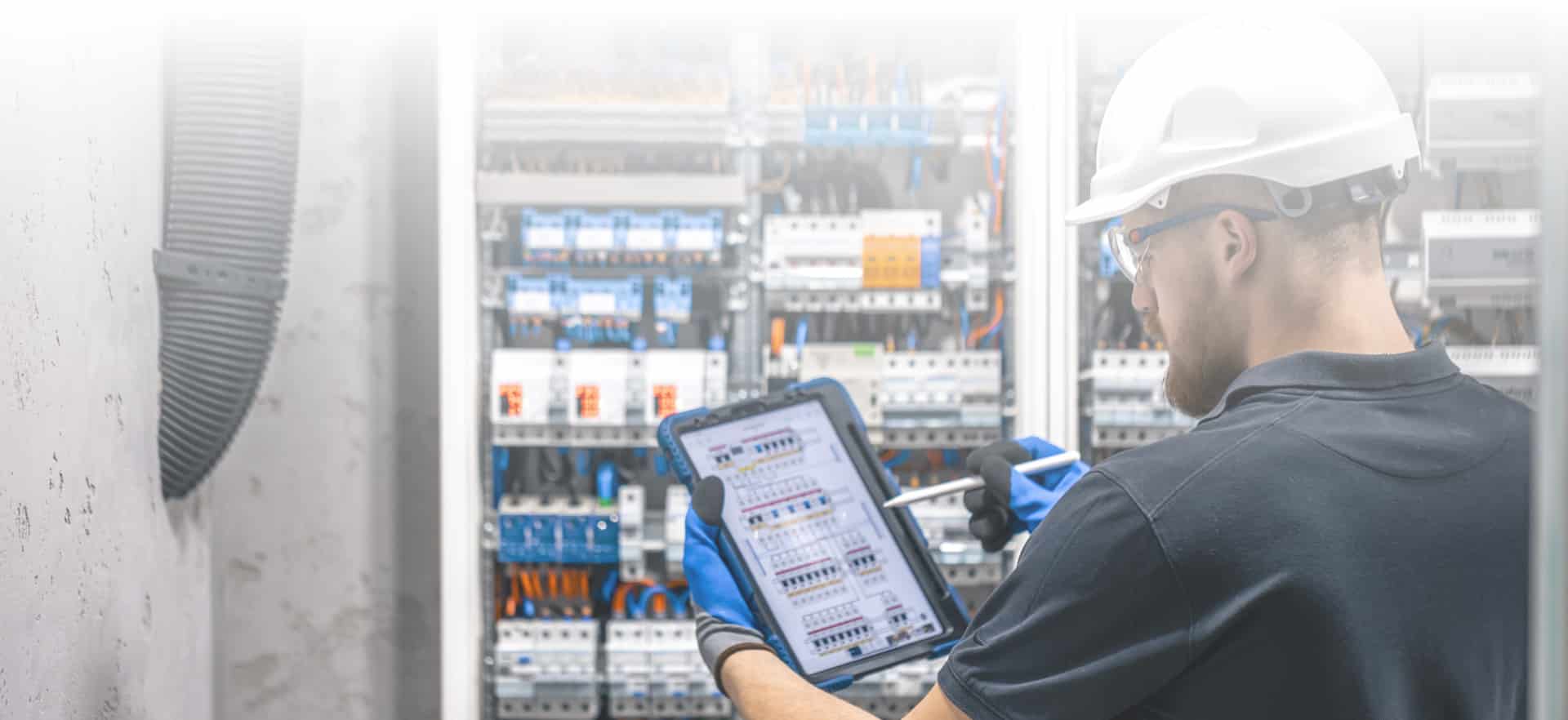 Electrician with a tablet at a panel